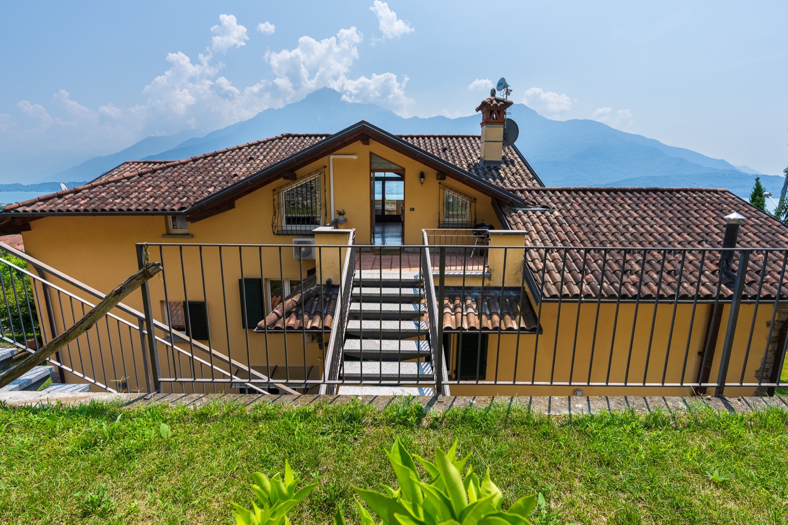 Esterno della casa gialla con scala e montagne