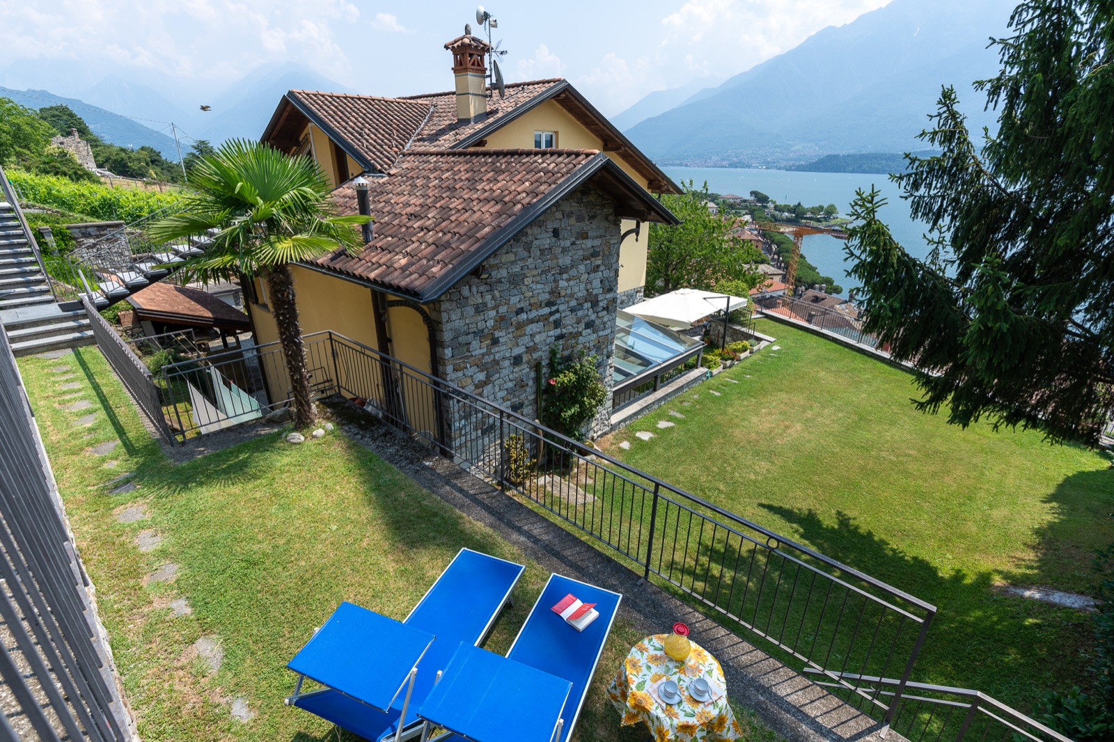Giardino terrazzato con lettini blu e il lago di Como dall'alto