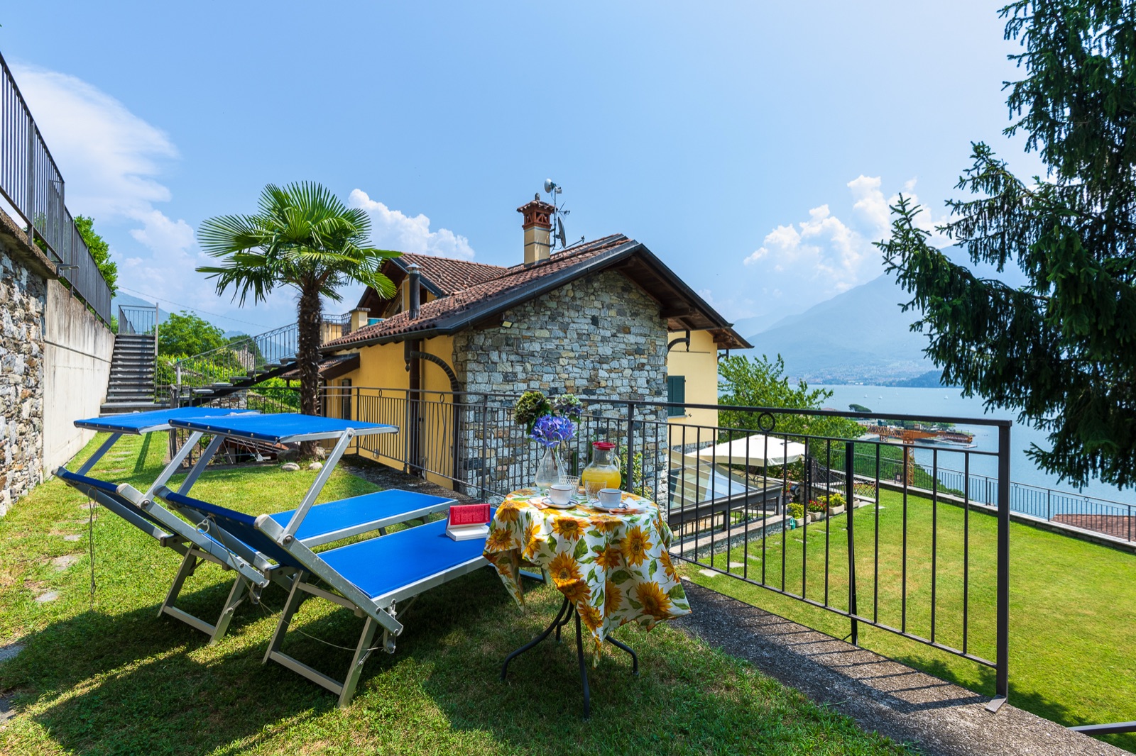 Giardino con lettini blu e colazione vista lago